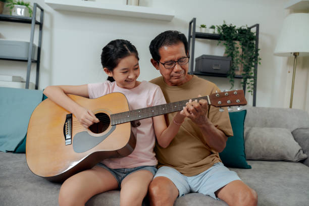 istock Grandfather teaching granddaughter playing guitar at home 1488536713
