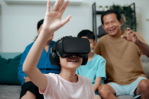 istock Granddaughter having fun augmented reality Technology in VR headset at home with grandparent . virtual reality Metaverse World. 1488536771