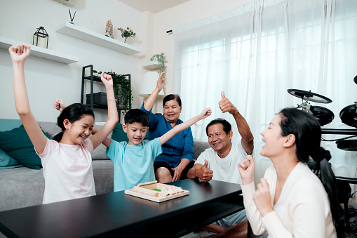 Asian family bonding together playing board game at home during the weekend