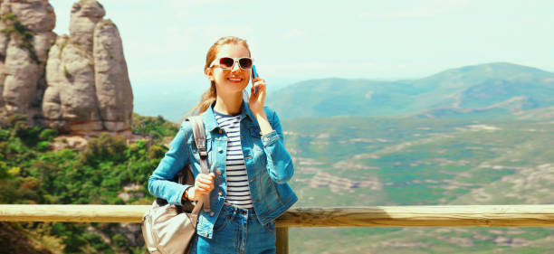 Travel concept, portrait happy smiling young woman calling on smartphone on hiking trail on top of the mountain Montserrat background stock photo