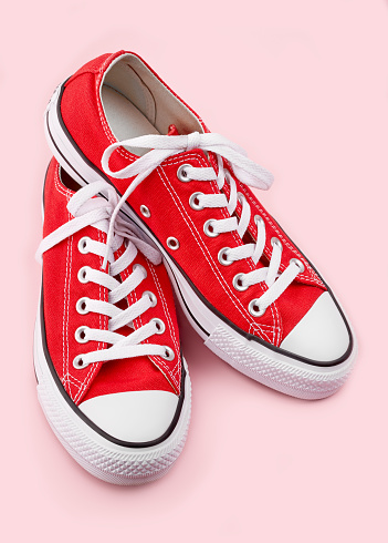 Red sneakers Red sneakers on pink background with copy space. Youth shoes.