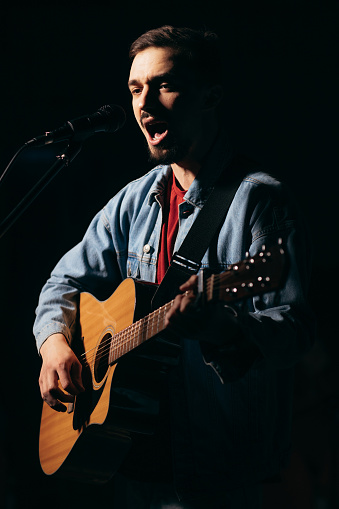 The singer plays an acoustic guitar and sings at a concert