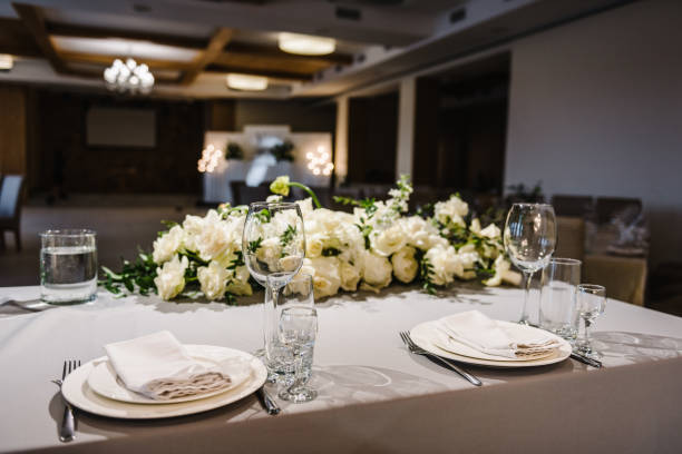 istock Festive table covered tablecloth, decorated composition flowers and candles in party area. Wedding setup detail. Table setting, serving. Banquet decoration in hall restaurant. Luxury reception. 1488539784