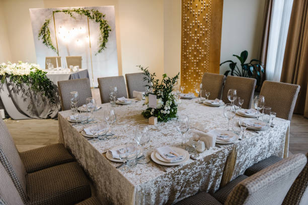 istock Wedding set up, dinner table reception. A plate with a napkin. Flower composition with greenery leaves in center of table and burning candles. Banquet decoration in hall restaurant. 1488539791