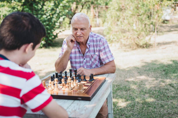Grandfather and grandson are playing chess together. stock photo