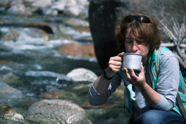 istock Female backpacker is taking water from mountain river 1488548622