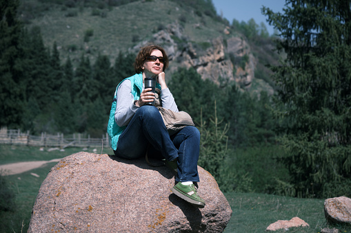Female mountain hiker is resting on the stone