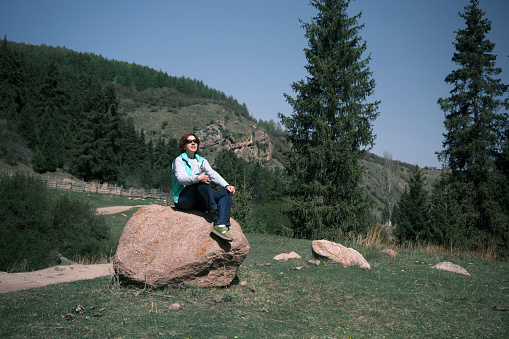 Female mountain hiker is resting on the stone