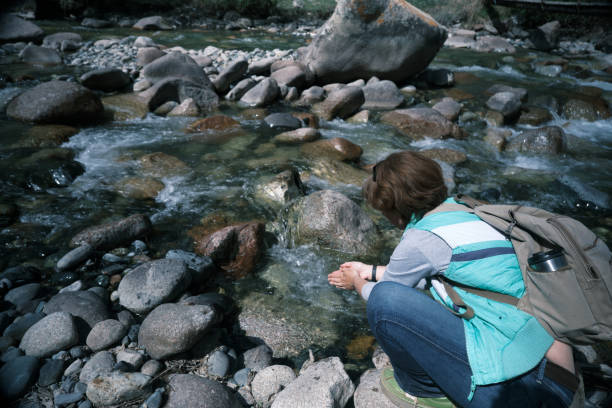 istock Female backpacker is washing hands in mountain river 1488549144
