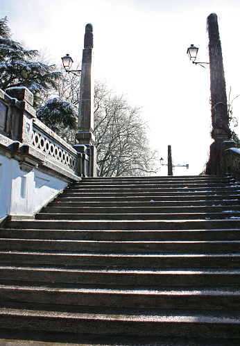 Monumental staircase in ancient public park in winter time. Lugo city, Galicia, Spain. Bare trees, wet flooring in rainy weather.