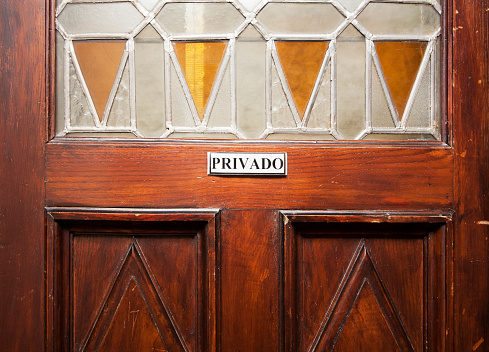 Private sign on retro style carved  door with stained glass, low angle close-up view.