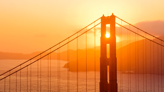 Aerial view of Golden Gate Bridge against orange sky during sunset, San Francisco, California, USA.