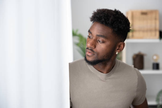 istock African american young man looking through window. 1488555991