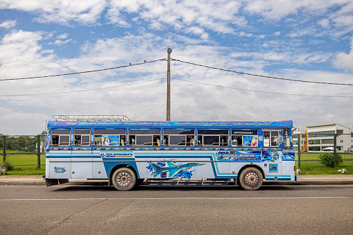 Galle, South Province, Sri Lanka - February 11th 2023:  Colorful bus with a picture of a F-16 jet fighter on the side parked in front of a power line