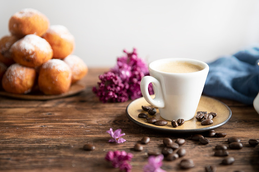 Fresh donuts with cup of coffee on the wooden table with space for text