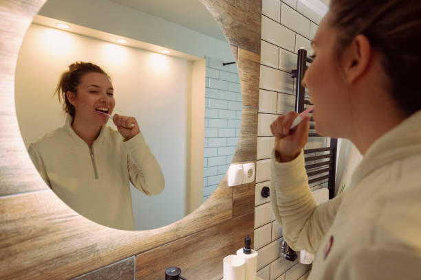 istock Cheerful woman brushing teeth in front of mirror 1488558827