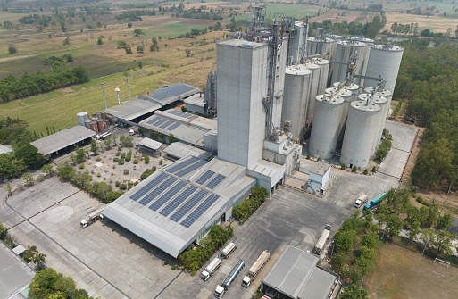 Aerial view of animal feed factory. Agricultural silos, grain storage silos, and solar panel on roofs of industrial plants. Industrial landscape. Agriculture industry. Factory with sustainable energy.