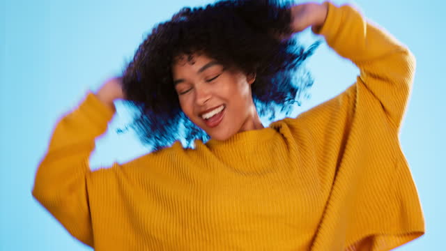 Happy black woman, dance and beauty in studio by blue background for fashion, smile and cheerful. Young gen z student, dancing and freedom with yellow clothes, curly hair afro and excited by backdrop