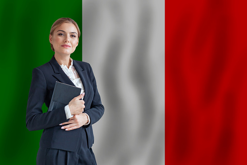 Formally dressed man in a three-piece suit holds a minature version of the South African flag.