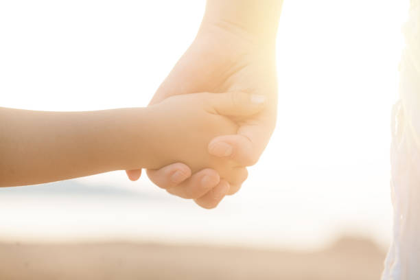 istock Child and parent hands on light background. Help, protection, family concept 1488565601