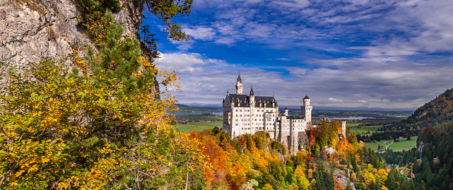 Fussen, Germany - August 7, 2015: Beautiful view of world-famous Neuschwanstein Castle, the nineteenth-century Romanesque Revival palace built for King Ludwig II on a rugged cliff, with scenic mountain landscape near Fussen, southwest Bavaria, Germany.