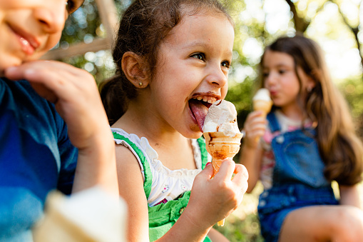 Cheerful children smiling and eating ice cream In the park