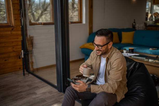 istock A middle-aged man in his cottage is lying on a large comfortable sack, which is placed next to a large window with a beautiful view of the nature outside. 1488566758