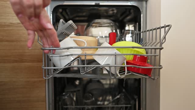 Girl hand with clean dishes inside of dishwasher
