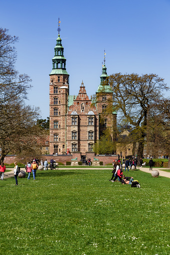 Copenhagen, Denmark - 29 April, 2023: people walking on the grounds and lawn outside Rosenborg Castle in central Copenhagen, Denmark.