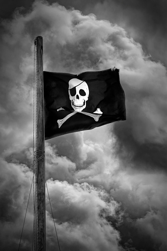 Pirate flag in black and white. Dramatic clouds.