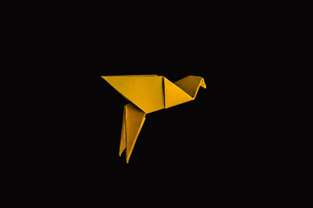 Orange Japanese origami paper crane follows yellow one, on white background