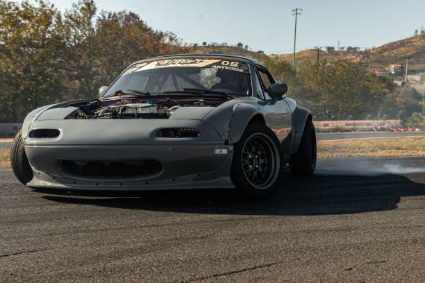 a mazda mia 2 on a race track making a burn out of a tire Athens, Greece – November 10, 2022: A shot of a Mazda Miata race car doing a burnout on a racetrack Revving stock pictures, royalty-free photos & images