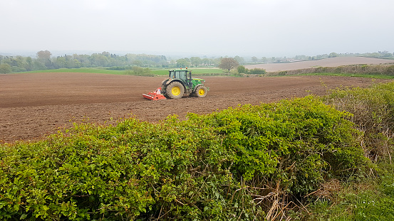Typically British, a tractor ploughing a field in the English countryside, preparing the soil for planting crops, agriculture at its best .