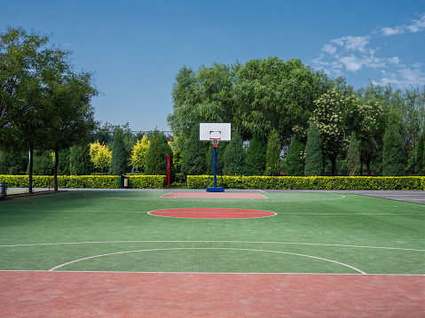 Outdoor public basket ball court near residential area with playground in the background