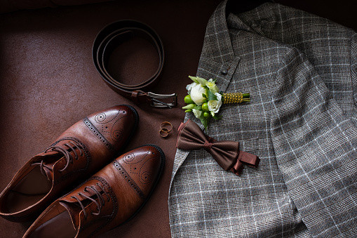 The groom's wedding accessories. A checkered jacket , a bow tie, brown shoes and a belt.
