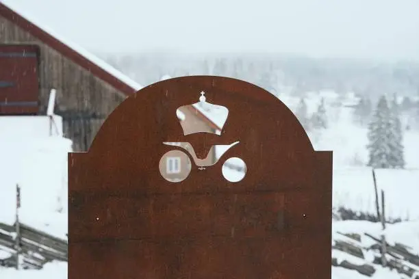 A rustic metal sign in shape of a vintage horse carriage