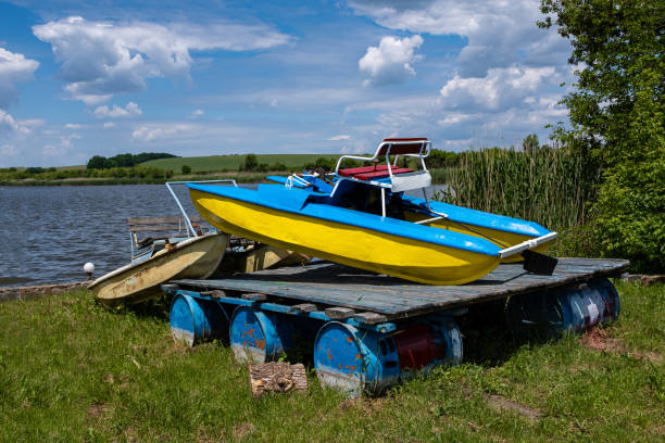 Old rusty and painted catamarans on the lake shore.
