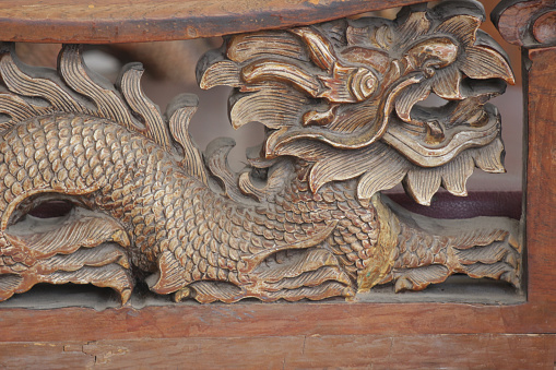 Intricately carved Chinese dragon in an old wooden panel