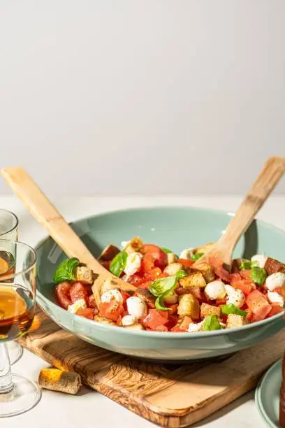 A closeup of a bowl of classic Panzanella salad with wooden spoons.