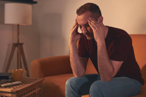istock Man with headache sitting on a sofa at home. 1488577948
