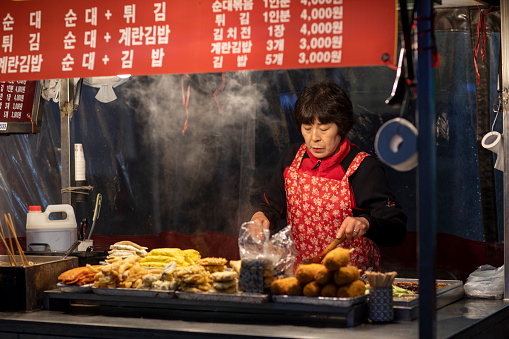 Seoul, South Korea - April, 2023 : A night street hawker preparing a  snack food for her buyers