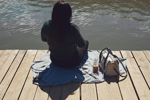 Woman relaxing on a sunny day at the lake wooden deck.