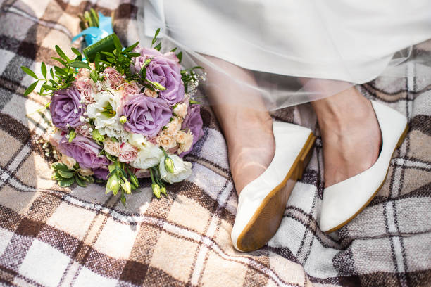 istock Bride's feet and wedding bouquet on brown blanket. Small rustic wedding, micro wedding 1488579936