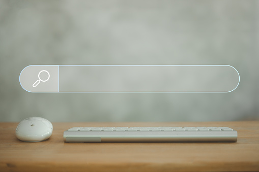 The computer keyboard and mouse are put on the wooden desk with an empty search bar to find what they are interested in. Searching information data on internet networking concept