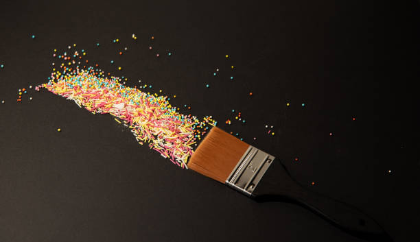 istock painting sprinkles, Creative sweet concept. Minimalistic composition with a brush and sprinkles on a black background. An idea for a tasty meal. Painting the world sprinkles 1488583127