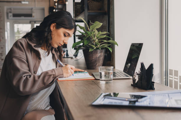 istock Attractive young woman making notes in her notebook in a cafe.Remote work, business, freelance,online education 1488583766