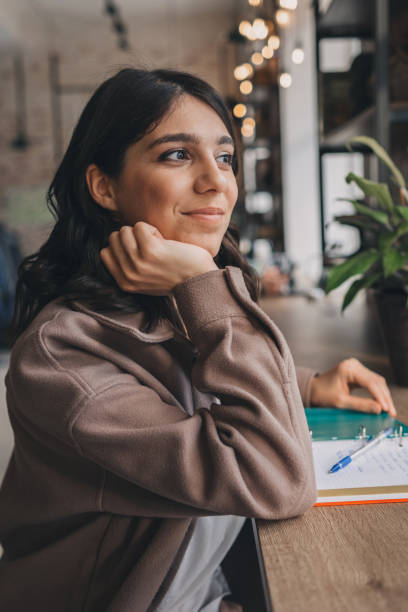 istock Attractive smiling young woman makes notes in her notebook in a cafe.Remote work,business,freelance concept 1488583779