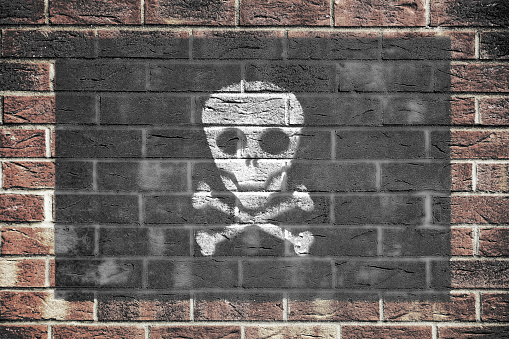 A Jolly Roger pirate scull and crossbones flag on old brick wall background