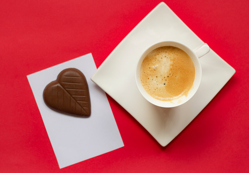 Heart shape chocolate and coffee on red background