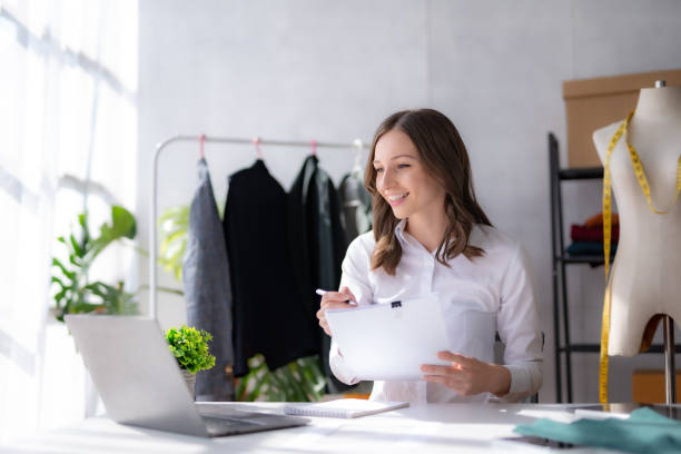 istock Attractive woman designer designing clothes for customers using laptop computer. 1488592194